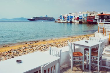 Ege Denizi 'ndeki kafe masası ve yolcu gemisi. Chora, Mykonos Adası, Yunanistan