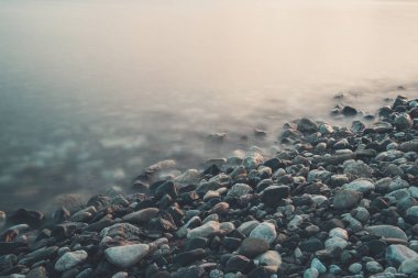 Deniz kıyıları, kayalar ve dalgalarla dolu rüya gibi doğal bir arka plan. Uzun pozlama