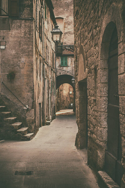 Narrow street of medieval ancient tuff city Pitigliano, travel Italy background