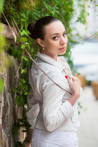白いズボンとジャケットを屋外でポーズの若い女性 — ストック写真