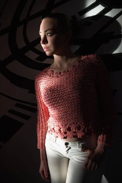 壁に近いポーズ ニットのセーターを着ている思いやりがある若い女性 — ストック写真
