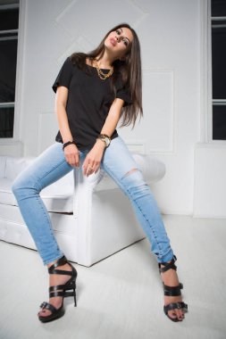 şık genç Bayan kot ve beyaz iç kanepede oturan siyah t-shirt