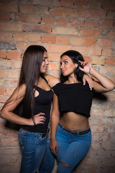 Two Sexy Brunettes Black Tops Jeans Posing Brick Wall — Stock Photo, Image