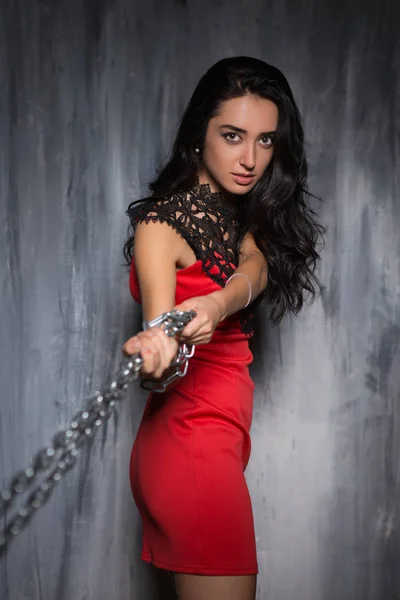 チェーンを引っ張る赤いドレスでセクシーな若い女性の肖像画 — ストック写真