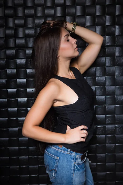 漂亮的年轻黑发女人在黑色 T恤摆姿势附近的墙壁 — 图库照片