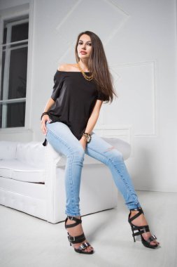 mavi kot pantolon ve siyah t-shirt beyaz iç kanepede oturan genç hanım