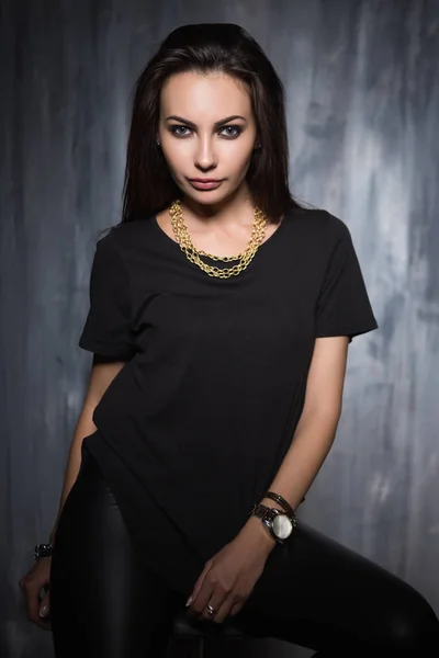 Ung Kvinna Poserar Trendiga Kläder Och Smycken Framför Grå Vägg — Stockfoto