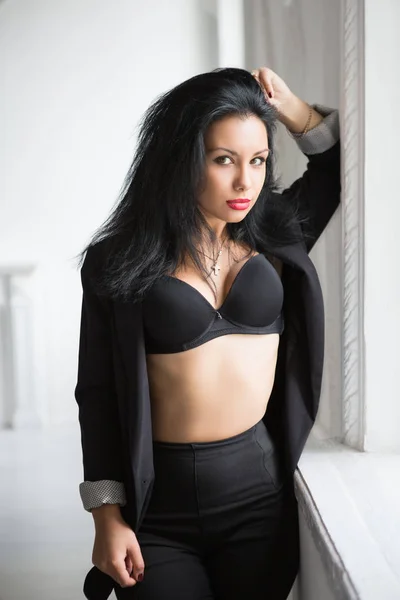 性感的年轻黑发在黑色衣服摆姿势附近的窗口 — 图库照片