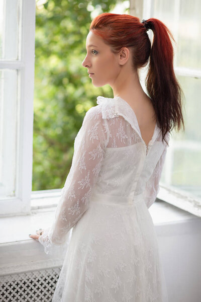 young lady with red hair in elegant white dress