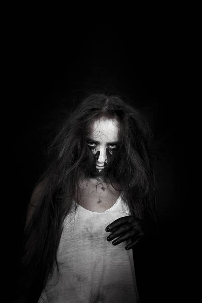 Portrait of a mad witch girl with long hair in the dark. the concept of Halloween and the day of the dead.
