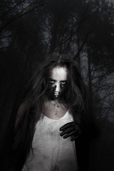 Portrait of a crazy witch girl with long hair in a dark forest. the concept of Halloween and the day of the dead.