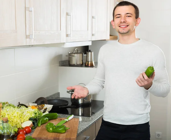 Homem cozinha com legumes na cozinha — Fotografia de Stock