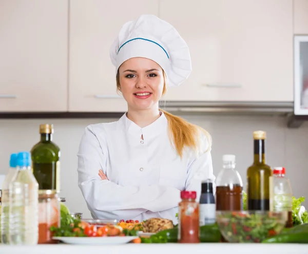 Happy cook preparing vegetable salad with cheese — Stock Photo, Image