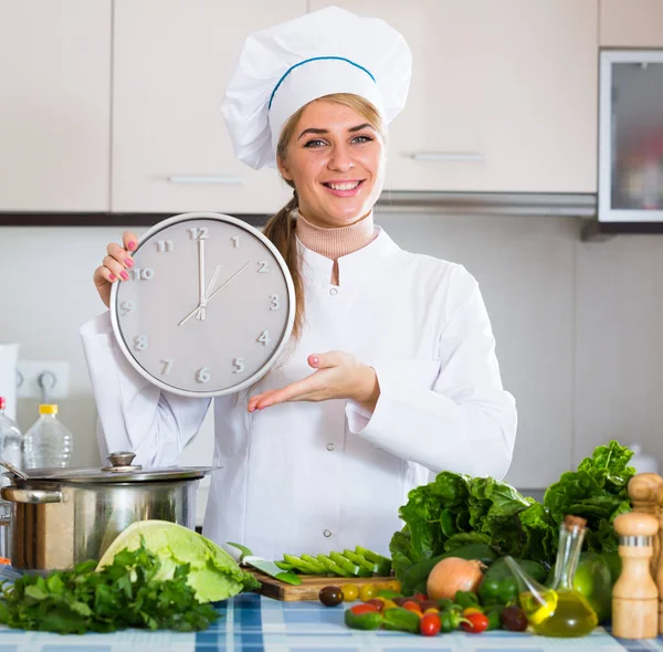 Meisje in chef-kok uniform met klok en groenten in de keuken — Stockfoto