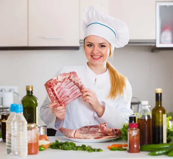 Female chef preparing lamb parts at kitchen table — Φωτογραφία Αρχείου