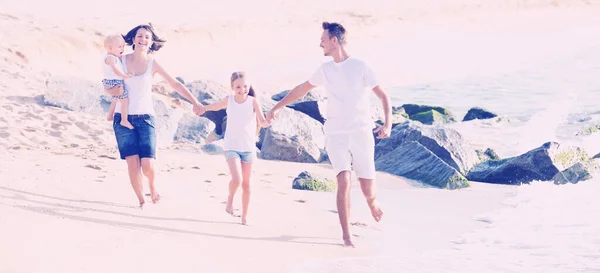 화창 한 날씨에 모래사장을 뛰어다니는 네 식구로 이루어 진한 가족 — 스톡 사진