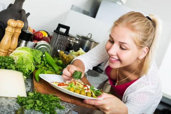 Женщина, подающая салат на кухне — стоковое фото