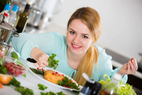 Dona de casa positiva com prato de salada na cozinha — Fotografia de Stock