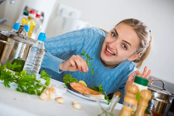Feliz chica adulta decorando pescado frito con hierbas —  Fotos de Stock