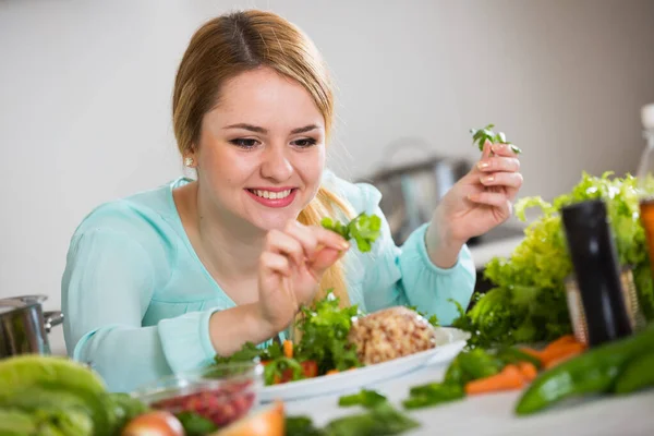 Junge Frau schmückt Salat mit Kräutern in Küche — Stockfoto