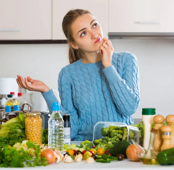 Giovane donna confusa che ricorda la ricetta per la cena in cucina — Foto Stock