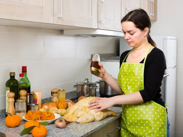 Frau bereitet Capon drinnen zu — Stockfoto