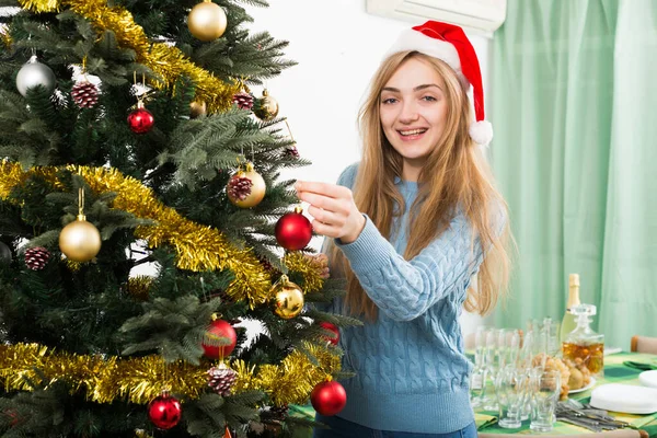 Jeune blondinette heureuse dans le chapeau de Père Noël près de l'arbre de Noël — Photo