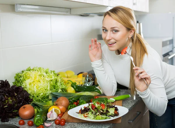 Menina feliz com salada de legumes na cozinha — Fotografia de Stock