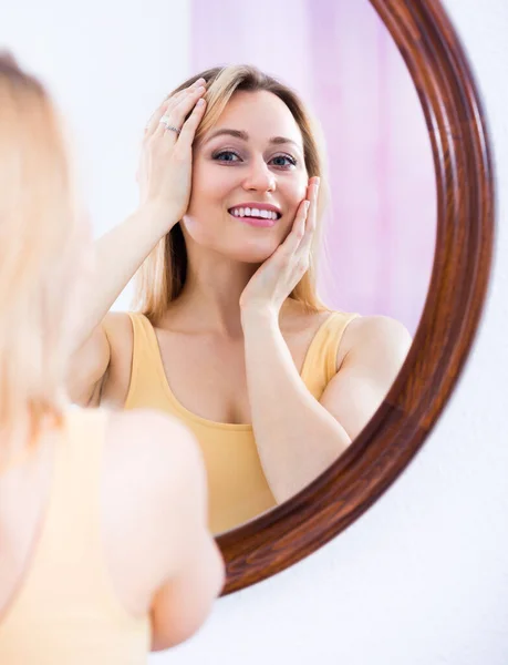 Glada Leende Långhårig Blondin Undersöker Hennes Ansikte Spegeln — Stockfoto