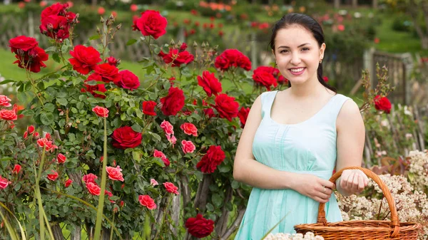 幸福的西班牙年轻女子的肖像 她在户外的玫瑰边提着篮子 — 图库照片