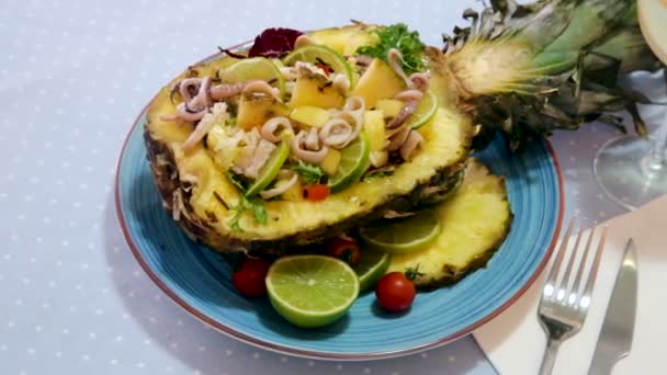 Sallad med calamari, ananas och lime serverad i ananas delad på mitten med dressing av anananasjuice, olivolja, lime och chilipeppar — Stockvideo