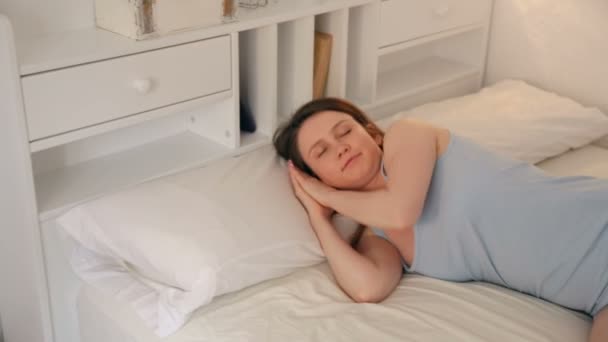 Χαλαρό κορίτσι στην πιτζάμα κοιμάται στο κρεβάτι στο εσωτερικό του σπιτιού — Αρχείο Βίντεο