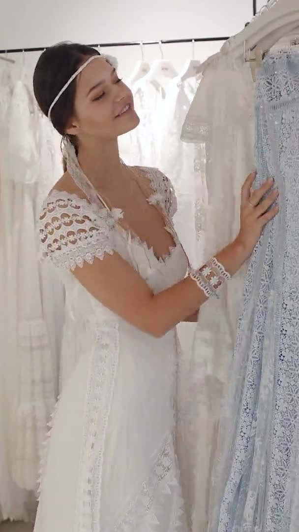 Mujer joven vestida con vestido blanco de lujo de pie en la tienda de bodas — Vídeo de stock