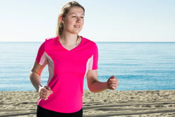 在海滩上进行户外运动时 体形匀称的女性慢跑 — 图库照片