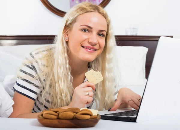 Blonde Frau Surft Internet Und Isst Cookies Bett — Stockfoto