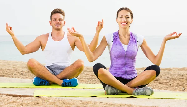 Couple training yoga on beach — Stock Photo, Image