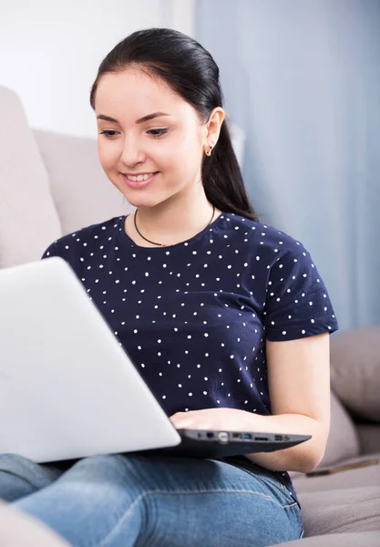 Glimlachend meisje op de bank met laptop — Stockfoto