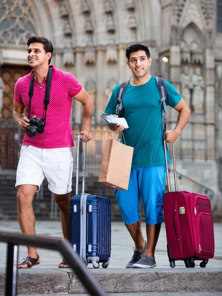 I turisti uomini stanno camminando con valigie in città sconosciuta. — Foto Stock