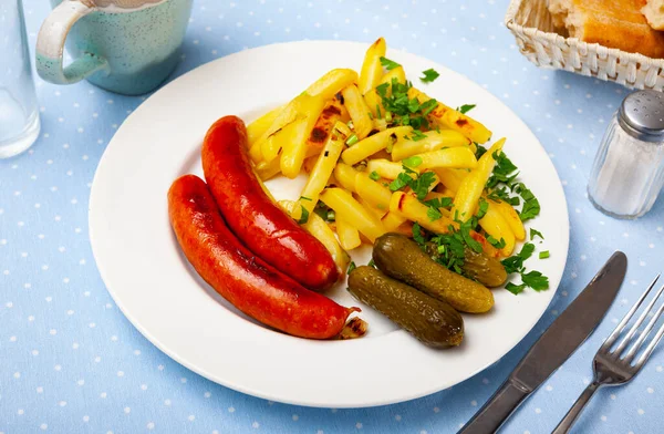 Запеченные сосиски с жареной картошкой и маринованными огурцами — стоковое фото