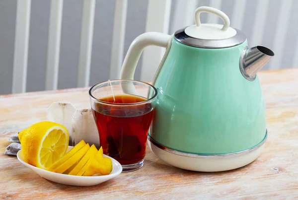 Сучасний електричний чайник, чашка і лимон на столі на кухні — стокове фото