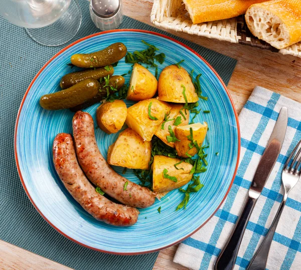 Saucisses appétissantes avec pommes de terre et concombres marinés gros plan — Photo