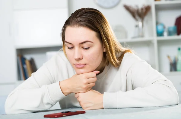 Young female is sitting with smartphone and boring alone — Stock Photo, Image