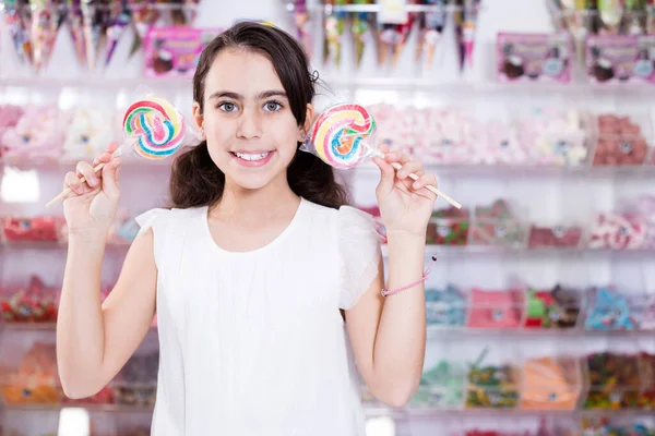 Emotional girl standing with colored candies on stick — Stock Photo, Image