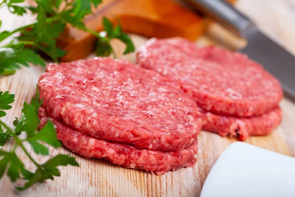 Close up of raw burger cutlet from pork on wooden table — Stock Photo, Image