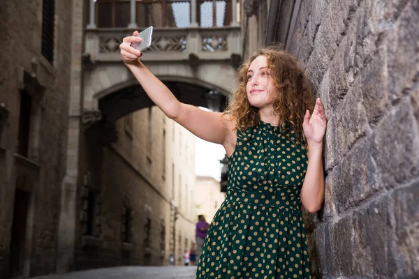 Fröhliches junges Mädchen steht nahe Ziegelmauer und macht Selfie mit Handy — Stockfoto