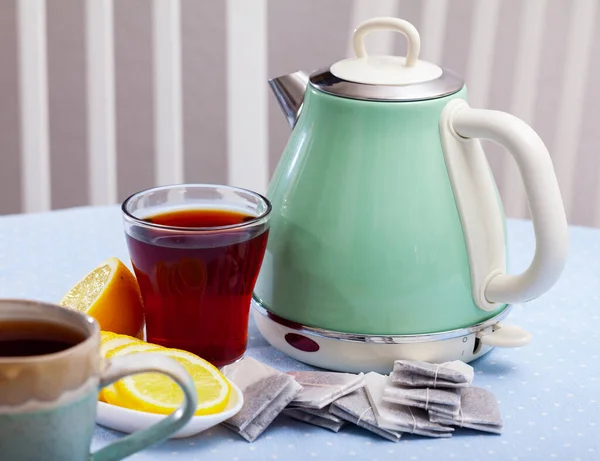 Nuova teiera sul tavolo con tazza di tè nero e limone affettato — Foto Stock