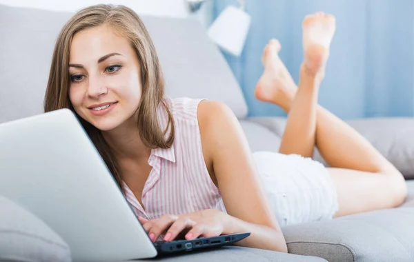 Chica descansando con el ordenador portátil en el sofá —  Fotos de Stock