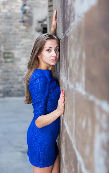Wesoła kobieta jest zabawnie pozowanie w niebieskiej sukience w pobliżu ściany — Zdjęcie stockowe