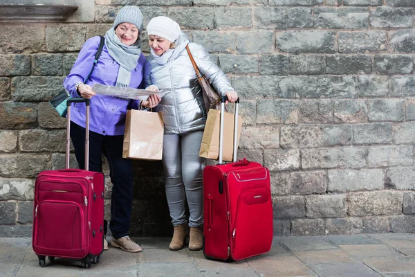 Senior ladies with suitcases and map near stone wall — Stock Photo, Image