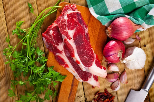 Filetto di manzo crudo con prezzemolo e aglio sul tavolo — Foto Stock